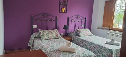 two beds in a room with purple walls at Pensión Boavista in Portomarin