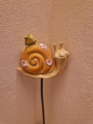 a toy snail on a pole against a wall at Casetta della chiocciola in Sassi