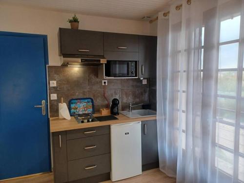 eine Küche mit einer Spüle und einer Arbeitsplatte in der Unterkunft Studio Les Trois Clés in Fressenneville