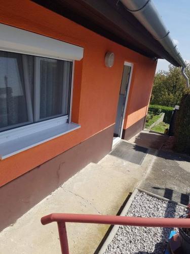 an orange building with a window and a door at Napfény szálló in Galambok