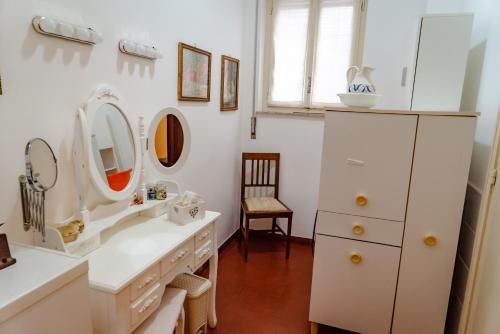 baño con encimeras blancas, espejos y silla en Antiquarium Messina, en Messina