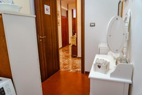 a bathroom with a toilet and a sink and a hallway at Antiquarium Messina in Messina