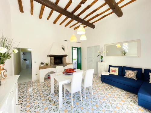 sala de estar con mesa y sofá azul en Villa Pomelia, Villa nel corso di Santa Marina Salina a 50 mt dal mare en Santa Marina Salina
