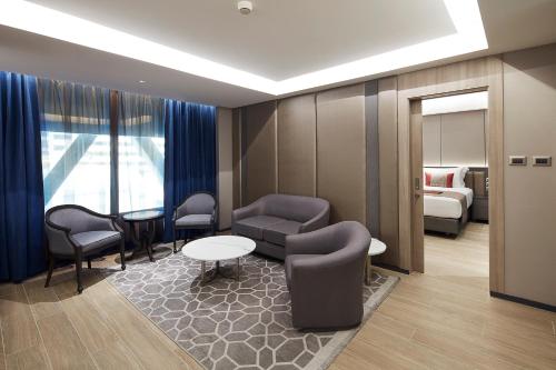 a hotel room with a bed and a couch and chairs at Grace At Five by Grace Hotel Bangkok in Bangkok
