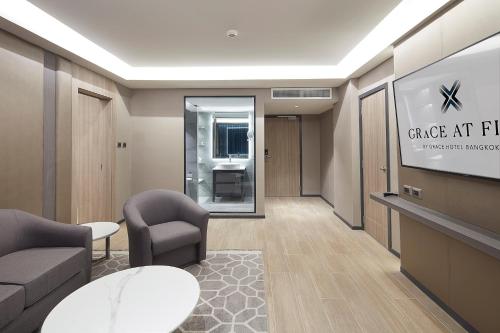 a lobby with a waiting room with chairs and a tv at Grace At Five by Grace Hotel Bangkok in Bangkok