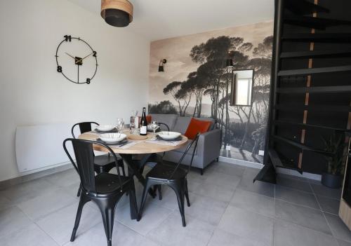une salle à manger avec une table, des chaises et une horloge dans l'établissement Maison la Cassine - Centre Doué la Fontaine - Proche Zoo, à Doué-la-Fontaine