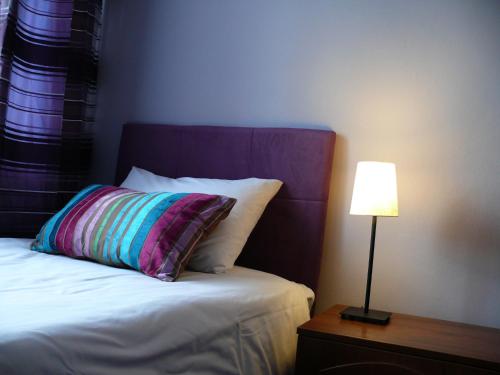 a bed with a colorful pillow next to a lamp at Dwór Zbożenna in Przysucha