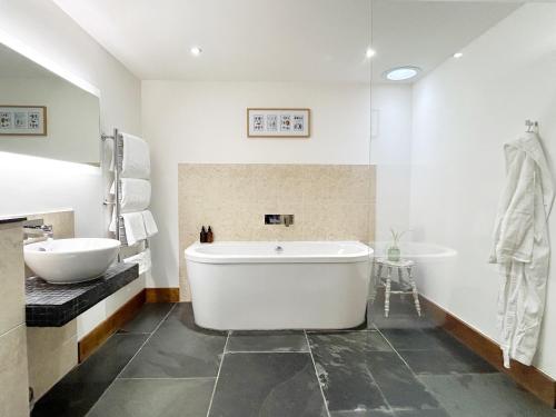 a white bathroom with a tub and a sink at Merlin Farm Cottages short walk to Mawgan Porth Beach and central location in Cornwall in Mawgan Porth
