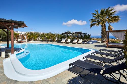 a swimming pool with lounge chairs and the ocean at Aquaria Villa in Karterados