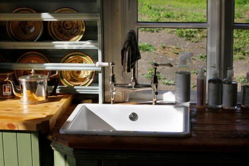 fregadero blanco en una cocina con ventana en Villa Leonore: Sommerhus m/strandlinje på Helgøya en Ringsaker