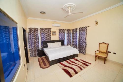a bedroom with a bed and a chair and curtains at Afranasa Inn in Tema