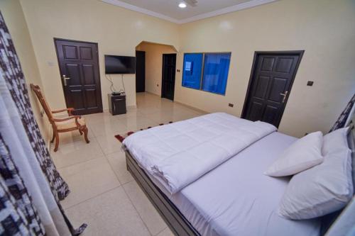 a bedroom with a bed and a chair and a television at Afranasa Inn in Tema