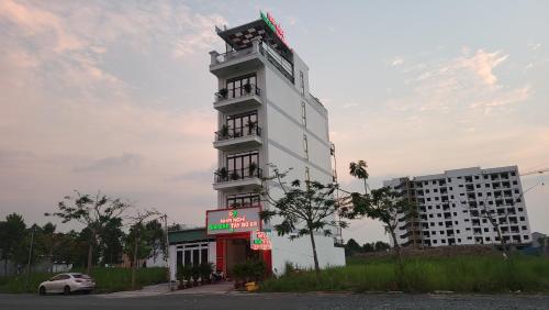 un edificio blanco alto con un cartel delante en Nhà nghỉ gia bảo tây đô 68 cần thơ, en Ấp Bình Thương