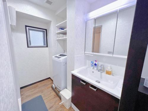 a white bathroom with a sink and a mirror at shizuka1 401 in Osaka
