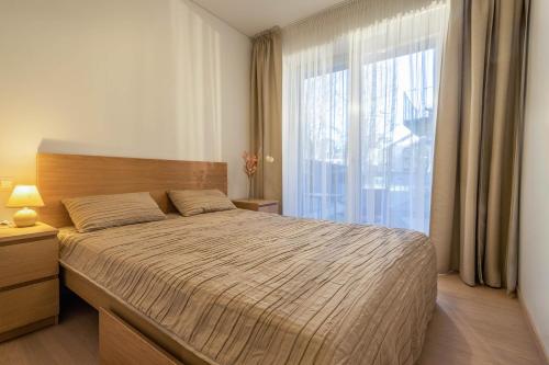 a bedroom with a large bed and a large window at Sunset Apartment in Juodkrantė