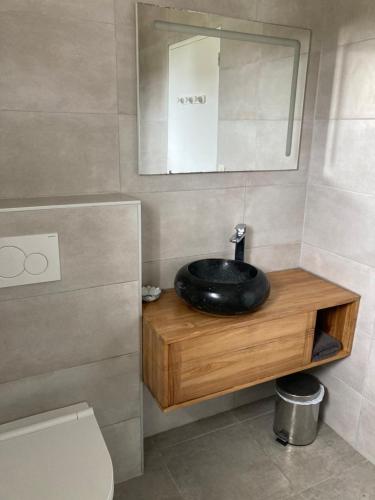 W łazience znajduje się czarna umywalka i lustro. w obiekcie Les Hortensias à 50 m de la plage de Trestraou w mieście Perros-Guirec