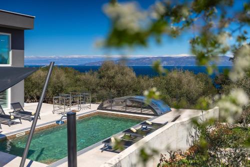 una piscina con sillas en una casa en Luxusvilla in Kroatien mit Pool und Meerblick, en Ravni