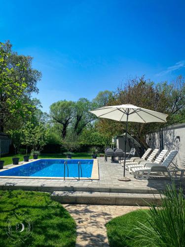 una piscina con sombrilla, sillas, mesa y sombrilla en Villa D Blagaj, en Blagaj