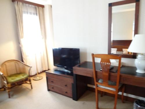 a room with a desk with a television and a mirror at Kyu Karuizawa Hotel Otowa No Mori in Karuizawa