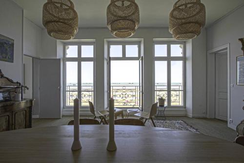 a dining room with a table and chairs and windows at Panoramic Mulberry Beach plendid family apartment in Asnelles