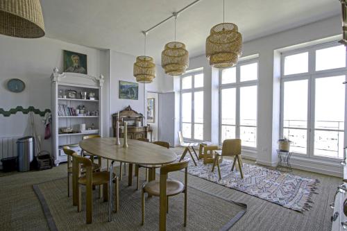 uma sala de jantar com mesa, cadeiras e janelas em Panoramic Mulberry Beach plendid family apartment em Asnelles
