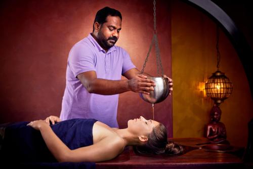 a man is offering a woman a pot at Ayurveda Resort MANDIRA in Bad Waltersdorf