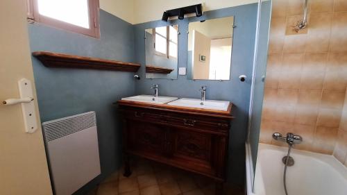 ein Badezimmer mit zwei Waschbecken, einem Spiegel und einer Badewanne in der Unterkunft Le Hameau du Pagnon in Saint-Mesmin