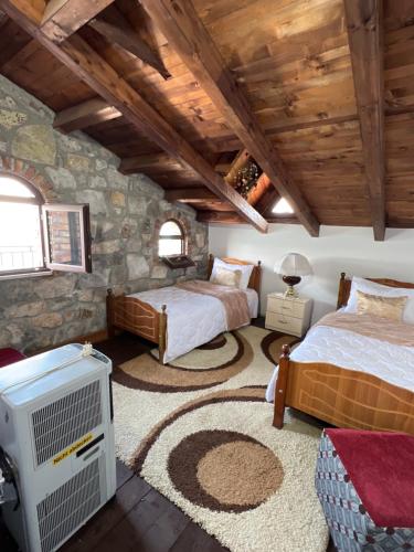a bedroom with two beds and a stone wall at Il Tramonto in Shirokë