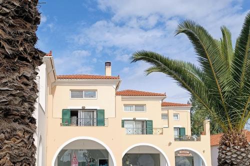 a large house with a palm tree in front of it at Hermione Port Luxury Residence in Ermioni