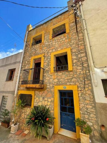 Edificio de piedra con puerta azul y balcón en Can Moletes, en Pratdip