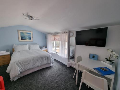 een slaapkamer met een bed, een bureau en een televisie bij The Garden Suite Holt in Holt