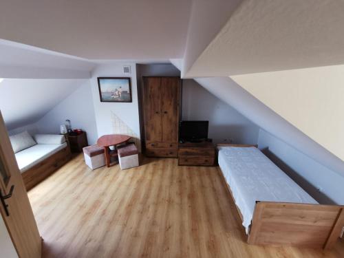 a attic room with a bed and a tv at Agrostrzecha in Ryczów