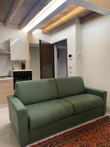a green couch in a living room with a kitchen at Fiera Home Verona in Verona