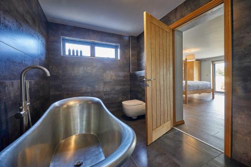 a bathroom with a tub and a toilet in it at Woodland Barn in Durham