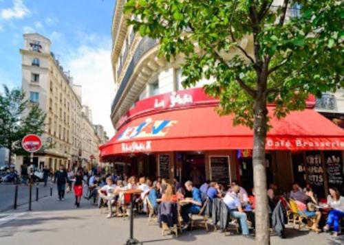 un grupo de personas sentadas en las mesas fuera de un restaurante en Le Bohème - Centre de Paris - Belle vue - Wifi en París
