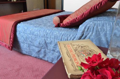 a book sitting on a table next to a bed at Gotha Hotel Turin Airport in Ciriè