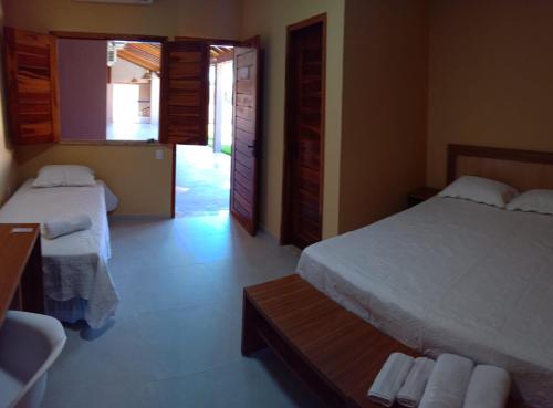 a bedroom with two beds and a table and a door at Hotel do Carmo in Piracuruca