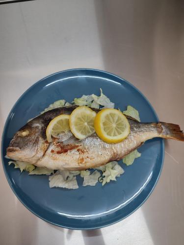 a fish on a blue plate with lemon slices at B&B Giardino Isabella in Palagiano
