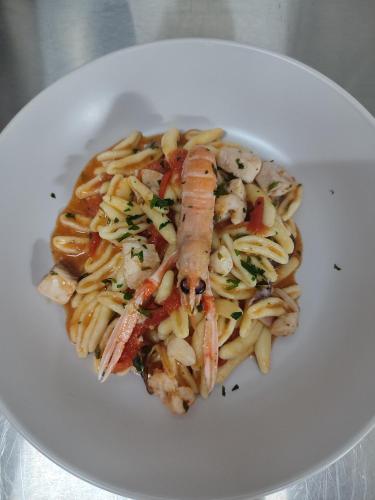 a white plate of pasta with a sausage on it at B&B Giardino Isabella in Palagiano