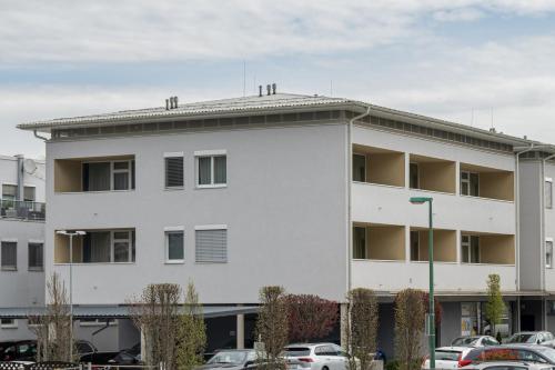 a white building with cars parked in a parking lot at PM-PremiumAPART Strassgang in Graz