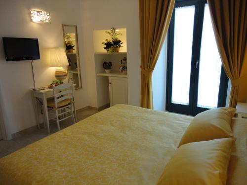a bedroom with a bed and a desk and a television at Masseria Santa Teresa in Monopoli