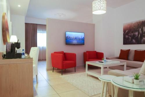 ein Wohnzimmer mit einem Sofa und roten Stühlen in der Unterkunft Toledo Amman Hotel in Amman