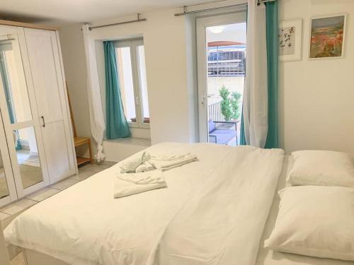 a white bed in a room with a window at Magoria, nel cuore della Città Vecchia di Locarno in Locarno