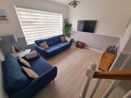 a living room with a blue couch and a tv at Private 2 bedroom house close to the beach in Paignton