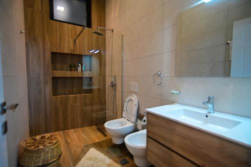 La salle de bains est pourvue de toilettes, d'un lavabo et d'un miroir. dans l'établissement Stylish two bedroom house with private pool, à Tirana