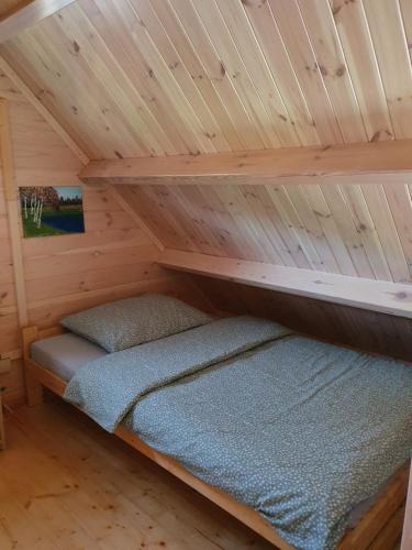a bed in a cabin with a wooden ceiling at Szteklin os. Nowe in Szteklin