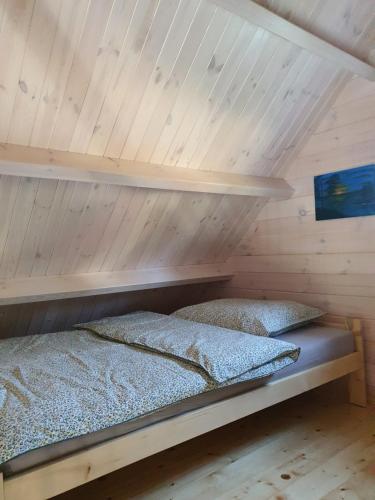 a bed in a room with a wooden ceiling at Szteklin os. Nowe in Szteklin