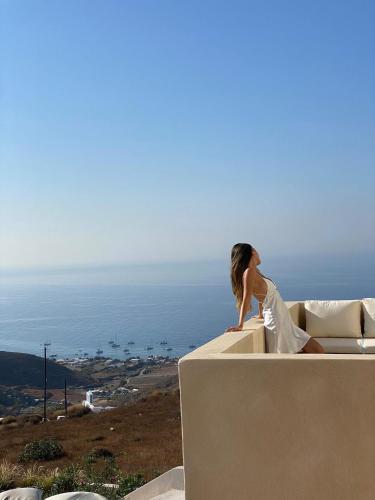 a woman sitting on a wall looking at the ocean at Akrorama private villas and suites in Akrotiri