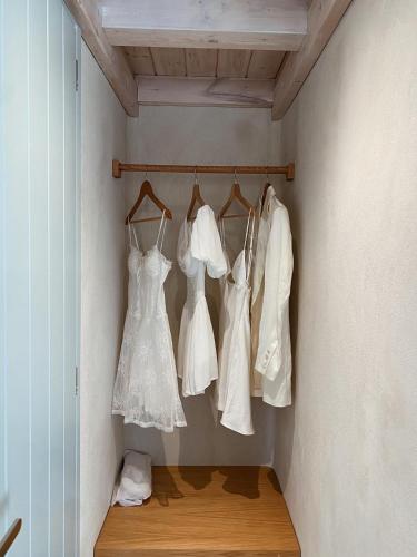 a row of white wedding dresses hanging on a wall at Akrorama private villas and suites in Akrotiri