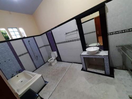 y baño con lavabo, aseo y espejo. en Ijen Transito 2 homestay, en Ketapang